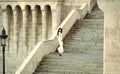 Sensual woman. Fashion bride in white wedding dress on staircase. Fashion model with long hair on stair steps Royalty Free Stock Photo