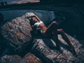 Sensual, sexy young girl with a seductive slim shapely body in a swimsuit is lying and posing on the rocks at night. Summer dark o Royalty Free Stock Photo