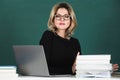 Sensual student woman in eyeglasses near blackboard. Sexy beautiful girl sit on table on chalkboard. Attractive female Royalty Free Stock Photo