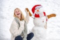 Sensual winter girl posing and having fun. Winter waman with Snowman on snow background. Winter portrait.