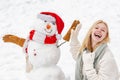 Sensual winter girl posing and having fun. Winter waman with Snowman on snow background. Winter portrait.