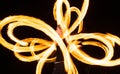 Sensual woman artist perform fiery twirly trails by spinning flaming pois during fire performance in night darkness