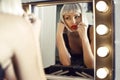 Sensual woman in blond wig doing makeup in dressing room Royalty Free Stock Photo