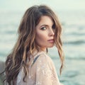 Sensual woman with long curly brown hairstyle on ocean background, romantic portrait Royalty Free Stock Photo