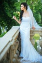 Sensual woman with wedding bouquet. Woman with flowers on balcony. Beauty girl with bridal makeup and hairstyle. Bride