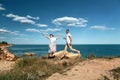 Sensual young couple in glasses in love jump on the rock in the sea near the beach with big cliffs. Man and woman looking on each Royalty Free Stock Photo