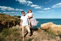 Sensual young couple in glasses in love jump on the rock in the sea near the beach with big cliffs. Man and woman looking on each Royalty Free Stock Photo