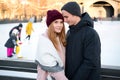 Young couple in love holding hands touching noses enjoying romantic moment together outdoors near ice rink in winter Royalty Free Stock Photo