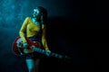 Sensual young hipster woman with curly hair with red guitar in neon lights. Rock musician is playing electrical guitar