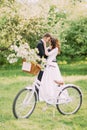 Sensual young newlywed couple holding each other in park. Bicycle with wedding decoration on foreground Royalty Free Stock Photo