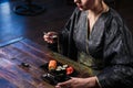 Sensual young woman in a geisha asian costume with fashion makeup and hair style eats sushi