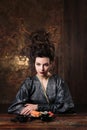 Sensual young woman in a geisha asian costume with fashion makeup and hair style eats sushi