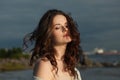 Sensual young woman model with brown hair and natural make-up walking along the shore of the resort on a spring morning. Happiness