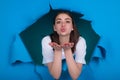 Sensual young woman send air kiss, isolated on studio blue paper hole. Kiss for you. Sensual woman send air kisses open Royalty Free Stock Photo