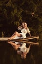 Sensual young woman sitting by the lake at sunset or sunrise posing Royalty Free Stock Photo