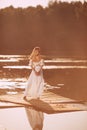 Sensual young woman standing by the lake at sunset or sunrise Royalty Free Stock Photo