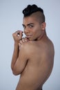 Sensuous transgender looking over shoulder while standing against gray background