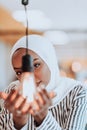 Sentimental portrait of African-American young female Muslim wearing hijab while holding a lightbulb.