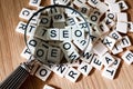 SEO concept with magnifying glass over SEO text spelled out from mixed letters