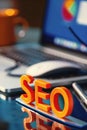 Seo concept, search engine optimisation, orange letters on office desk