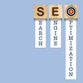 SEO concept. Search engine optimization. Word on wooden blocks, over blue background Royalty Free Stock Photo