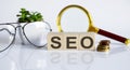 SEO concept on wooden cubes and flower ,glasses ,coins and magnifier on the white background Royalty Free Stock Photo