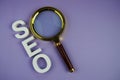 SEO letters and magnifying glass top view on purple background Royalty Free Stock Photo