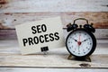SEO Process text on paper card with alarm clock on wooden background Royalty Free Stock Photo