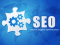 SEO with puzzle and world map, search engine optimization, flat Royalty Free Stock Photo