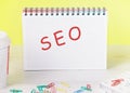 Seo the word is written on a blank sheet in a notebook standing on a table on a yellow background