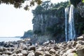 Tourists climbing on the stones at the Jeongbang waterfall in Seogwipo, Jeju Island, South Korea Royalty Free Stock Photo