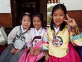 Three smiling girls dressed in Hanbok, traditional Korean dress at Namsangol Hanok Village in Seoul