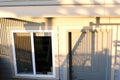 Separate basement apartment entrance with stairs, glass panel and trees on the lawn at the side. There is a electricity