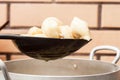 Separate the finished ravioli from the water in a sieve over a saucepan against a brick wall of decorative brick in the kitchen