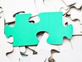 Separate green piece on pile of white jigsaw puzzles