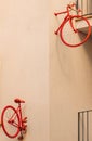 The separated front and rear half of a vintage red bicycle pinned to the wall of a minimalist building block