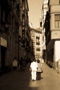 Sepia colored street picture of the old city of Bilbao, with two elderly woman walking arm in arm through the historical city