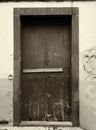 Sepia monochrome image of an old weathered wooden door nailed shut with a wooden bar and flaking paint on an outside wall Royalty Free Stock Photo