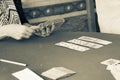 Sepia toned aged image effect of hand holding the cards playing card during day in Greek hill village bar