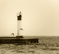 Sepia toned image of lighthouse on a pier with flying birds silhouetted Royalty Free Stock Photo