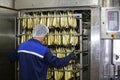 Fish factory.A worker pushes a smoked fish cart into an industrial oven.