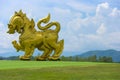 2018 September 29. CHIANG RAI THAILAND. A big golden lion statue standing at green grass yard and surrounded by natural mountain a