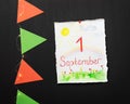 White sheet with a child's drawing and inspiration first september, paper flags and a light garland on a chalkboard