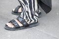 Model wears black buckle sandals without socks and zebra pants