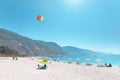 People resting and swimming on parasols and sunbeds on a popular public beach in resort town