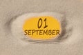September 1. 1th day of the month, calendar date. Hole in sand. Yellow background is visible through hole