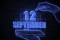 September 12th. A hand holding a phone with a calendar date on a futuristic neon blue background. Day 12 of month.