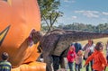 Dinosaur looking into a bouncy pumpkin at an event