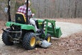 Senior man rides John Deere tractor on edge of rocky path