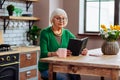 Septuagenarian silver-haired looking through Bible book sitting at kitchen table